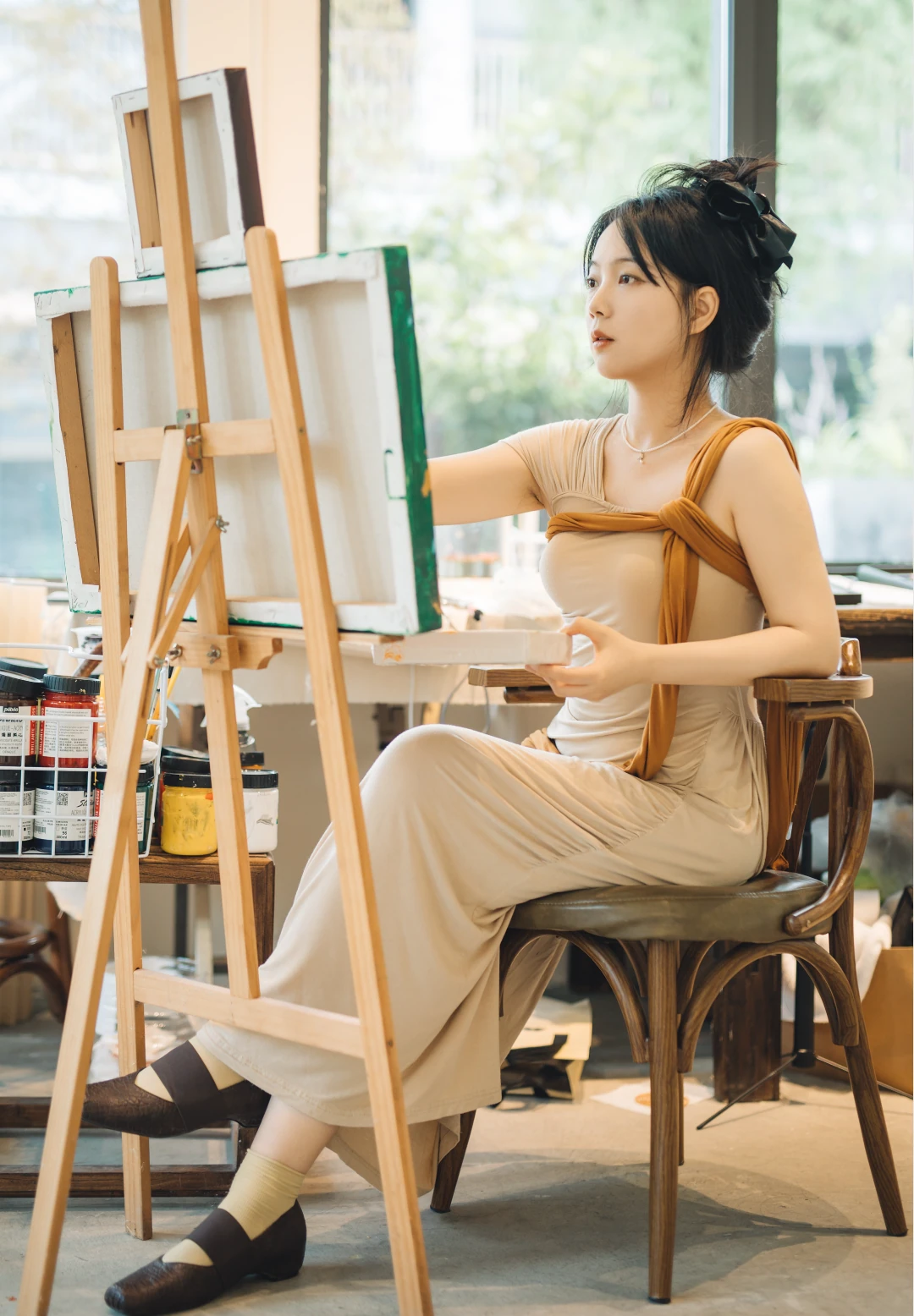 Na Xin seated at an easel, working with a brush during The Seed Within residency.